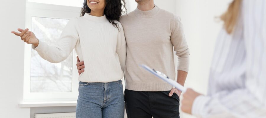 Una pareja joven y feliz visitando una casa y escogiéndola para ser su nuevo hogar.