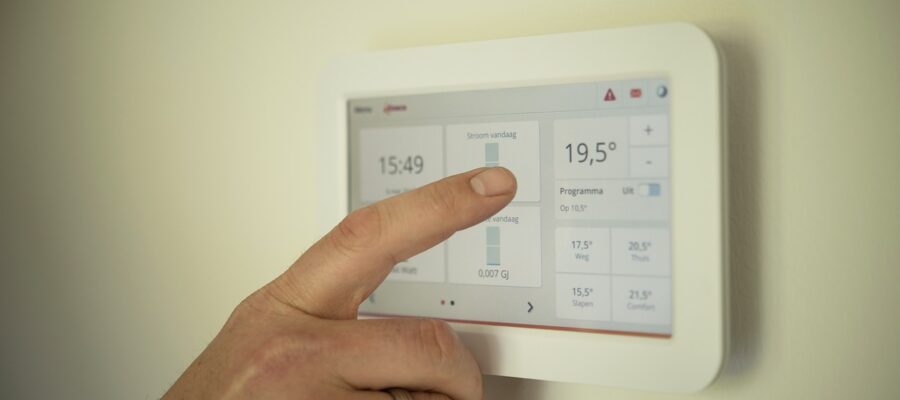 Una mano seleccionando en un termostato la temperatura ideal de la calefacción para la casa, según los criterios de biohabitabilidad para vivir en una casa sana.