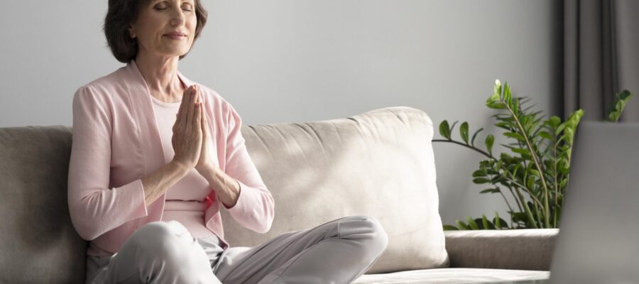 Mujer mayor, sentada en el sofá de su casa y en posición de meditación. Ambiente zen, relajado y preparado para la meditación según el Feng Shui.